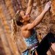 Woman in climbing gear climbing up cliff