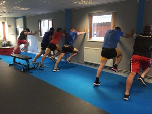 Group performing stetches against wall