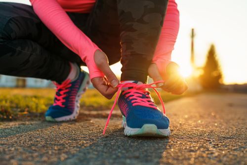 Fotolia_143293982_Subscription_Monthly_M Running shoes - woman tying shoe laces. Closeup of female sport fitness runner getting ready for jogging outdoors